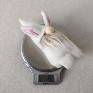 Detailed view of an Easter bunny gnome plush being weighed on a digital kitchen scale