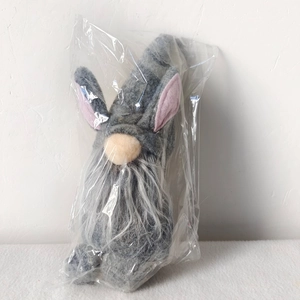 Close-up of Easter plush gnome with grey rabbit ears and white fluffy beard in clear bag