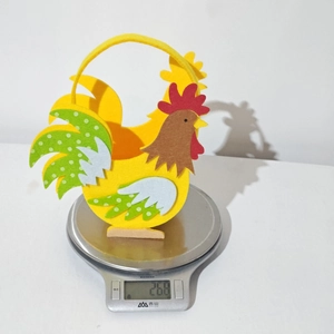 Detail eines bunten Filz-Osterhahns mit 26,8g Gewicht auf einer digitalen Waage