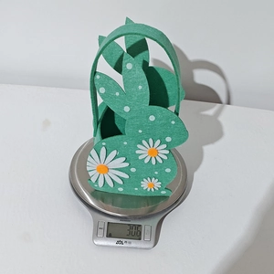 Detailed view showing the weight of a green felt Easter bunny basket on a digital scale