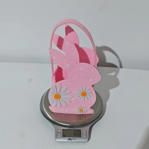 Pink felt Easter bunny basket with daisy flowers being weighed on a kitchen scale