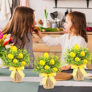 Close-up of Easter lemon leaf plant with yellow egg ornaments and burlap bow base