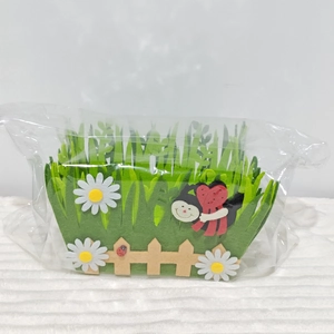 Detail of felt Easter storage basket with grass and ladybug in plastic packaging
