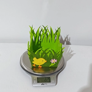 Close-up of lightweight green felt grass basket featuring a yellow chick and pink flower