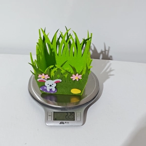 Lightweight 22.9g green felt Easter basket with rabbit design on an electronic scale