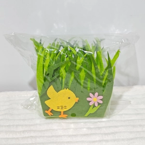 Close-up of Easter non-woven storage basket with chick and flower decor in plastic packaging