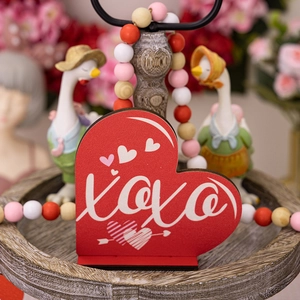Close-up of red XOXO heart wooden sign with colorful wood bead garland for Valentine's day