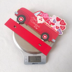 Red Valentine's truck wooden ornament with hearts being weighed on a kitchen scale