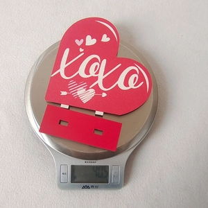 Close-up of red XOXO wooden heart sign being weighed on a scale for decor