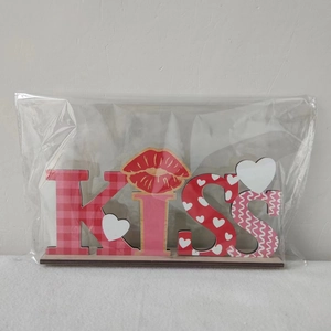 Detail of KISS wooden letter ornament with red plaid pattern in clear plastic wrap