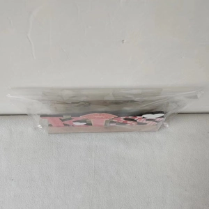 Close-up of pink wooden KISS sign with red lip print and heart patterns in packaging