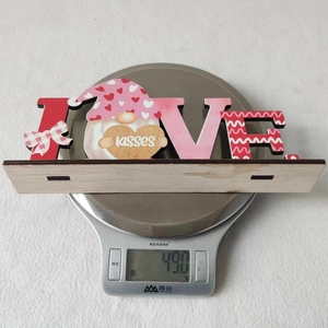 Weight measurement of a wooden LOVE gnome sign for Valentine decoration, showing 49.0 grams