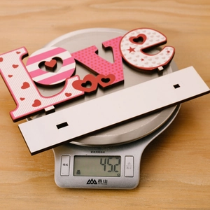 Détail de la décoration LOVE en bois montrant le poids de 45,2g sur une balance précise