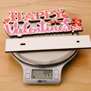 Gros plan d'une déco de la Saint-Valentin en bois sur balance pesant 44,7 g
