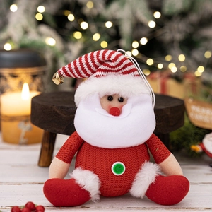 Close-up of plush Santa Claus ornament with red knit hat and golden bell decoration