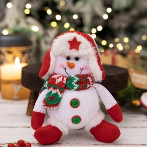 Close-up of a Christmas snowman plush with red trapper hat and striped green scarf