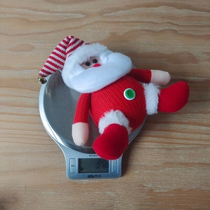 Macro shot of 34.6g knitted Santa Claus doll on a scale showing light product weight