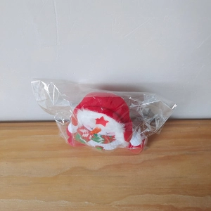 Close-up of a plush snowman figurine with a red hat and plaid scarf in clear packaging