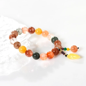 Colorful natural gemstone bead bracelet with a yellow leaf pendant on a cool ice-like setup