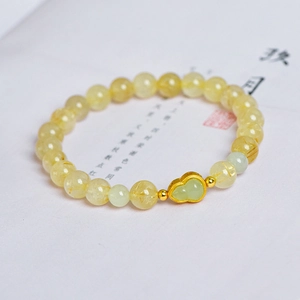 Golden rutilated quartz 7mm beaded bracelet with Hetian jade gourd charm on book page