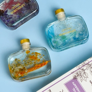 Three crystal aromatherapy glass bottles with dried flowers and colorful stones