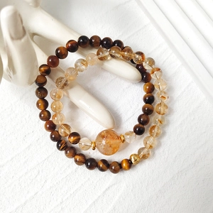 Tiger eye and yellow quartz beaded bracelet set on a white ceramic hand display