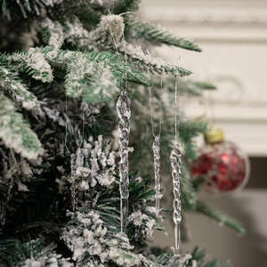 Macro detail of twisted acrylic ice icicle ornaments hanging on a snowy Christmas tree