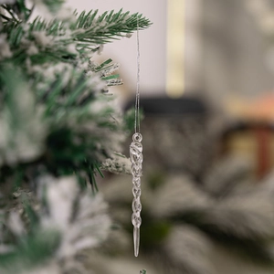 Macro view of transparent acrylic spiral icicle ornaments hanging on a snowy Christmas tree
