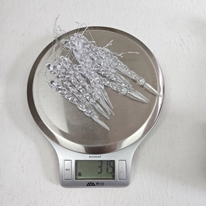 Detailed view of 12 transparent acrylic icicle ornaments on a scale weighing 37.5g