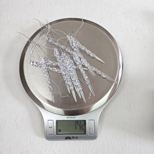 Close-up of 12 transparent acrylic icicle ornaments on a scale weighing 14.2g total