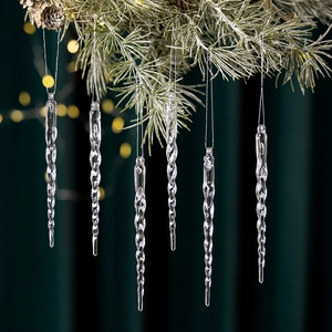 Close-up of twisted clear acrylic icicle ornaments hanging on a pine tree with lights