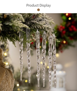 Detailed view of clear acrylic icicle ornaments hanging from snowy pine branches
