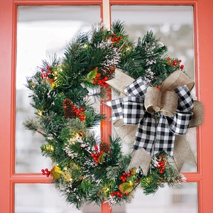 Close-up of lighted Christmas wreath with pine cones and buffalo plaid ribbon bow