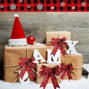 Festive red and black plaid Christmas bows on a rustic wooden background with gift boxes