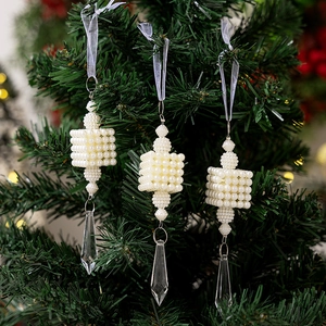 Close-up of pearl beaded Christmas ornaments with crystal pendants on green tree branches