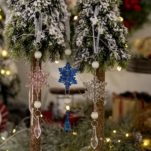 Close-up of acrylic snowflake crystal pendant with beads on a snowy Christmas tree