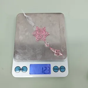 Detailed view of pink acrylic snowflake ornament on a digital scale weighing 12.3 grams