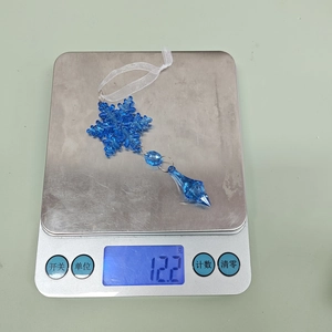 Close-up of blue acrylic snowflake ornament with water drop pendant on a scale