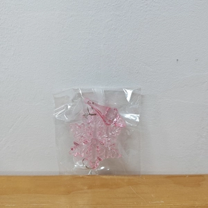 Close-up of pink transparent acrylic snowflake ornament with a teardrop crystal pendant