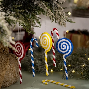 Detail of red and white spiral lollipop and candy cane ornaments on a snowy Christmas tree