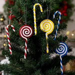 Close-up of red and white candy cane ornaments hanging on a festive Christmas tree branch
