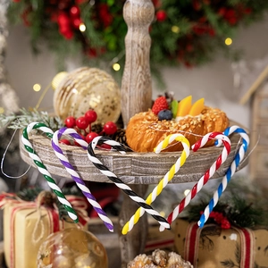 Close-up of colorful Christmas candy cane ornaments on a festive wooden display tray