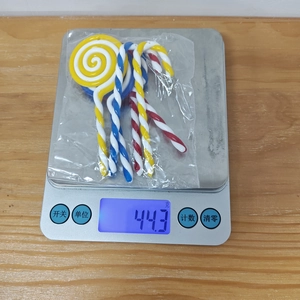 Macro detail of assorted colorful Christmas candy cane ornaments on a digital scale