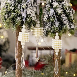 Three-piece pearl Christmas ornament set with crystal icicle drops on a snowy tree branch