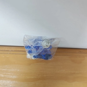 Detalle de colgante de cristal azul con adornos plateados y elegante cinta de seda blanca