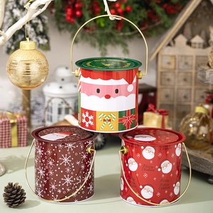 Vue détaillée de seaux de Noël en métal rouge avec poignées et motifs de fête