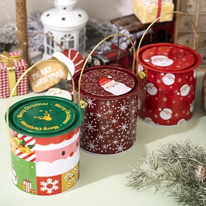 Détail de seaux de Noël en fer-blanc avec poignée métallique et motifs festifs de Père Noël