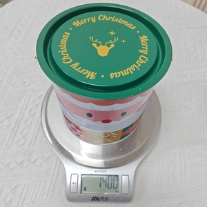 Détail de la boîte de Noël en fer blanc pesant 140g sur balance avec couvercle festif