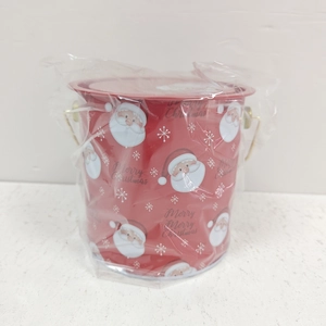 Vue détaillée d'une boîte de Noël rouge en métal avec poignée et motifs de fête