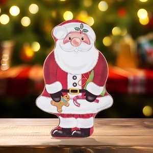 Detailed view of Santa Claus shaped tin box on wooden table with bokeh Christmas lights